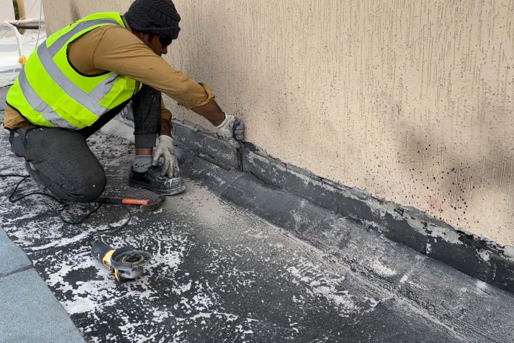 DCX technician reconstructing roof waterproofing chamber and perimeter detailing at Omar Bin Al Khattab Mosque during roof restoration works.